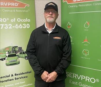 Clark standing in front of two SERVPRO green banners