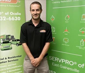 Joseph standing in front of two SERVPRO green banners