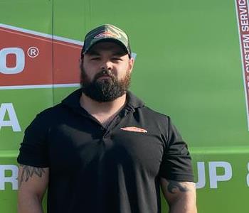 Anthony standing in front of a SERVPRO green van